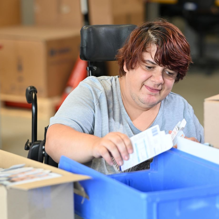 Melanie Lux, mit kurzem, dunklem Haar, beim Packen der Nahrungsergänzungsmittel.